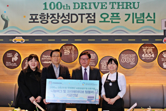 스타벅스코리아는 드라이브 스루 100번째 매장을 경북 포항 장성동에 열었다. 이날 포항장성DT점 오픈행사에 참여한 이석구 스타벅스코리아 대표(왼쪽에서 두 번째)와 직원들이 권순관 포항 북부장애인종합복지관 권순관 관장(왼쪽에서 세번째)에게 '나눔머그 및 텀블러'로 모인 기금을 전달한 뒤 기념촬영을 하고 있다. <스타벅스코리아 제공>